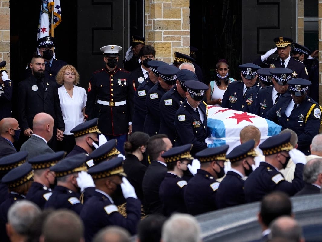 Elizabeth French, in white, and her son Andrew, left, follow the casket of her daughter, Chicago police officer Ella French, after a funeral service at the St. Rita of Cascia Shrine Chapel Thursday, Aug. 19, 2021, in Chicago.