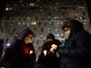 People hold candles during the candlelight vigil outside the apartment building which suffered the city's deadliest fire in three decades, in the Bronx borough of New York, on Tuesday, Jan. 11, 2022.