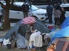 A woman eats at her tent at the Echo Park homeless encampment at Echo Park Lake in Los Angeles, on March 24, 2021.