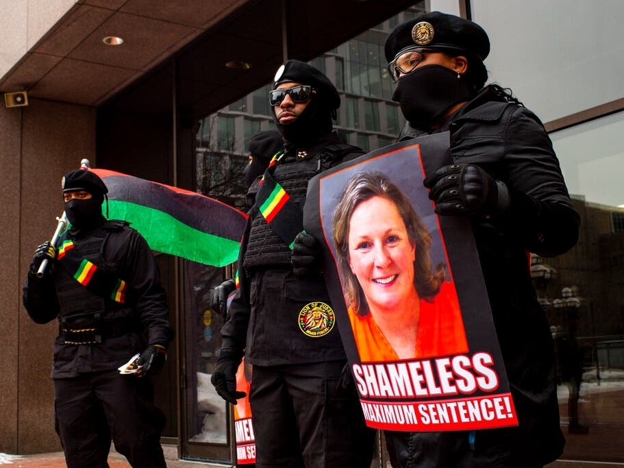Members of the New Black Panthers stand with signs calling for a maximum sentence for former Brooklyn Center Police Officer Kim Potter.