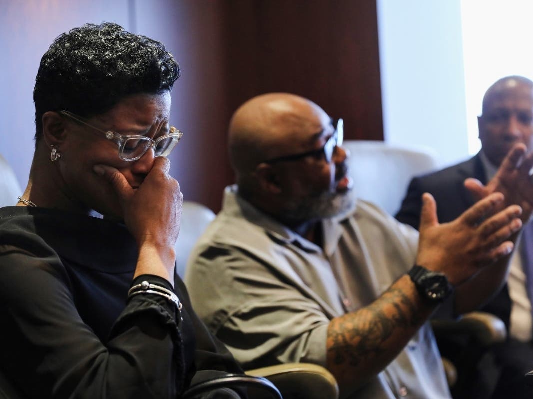 Veldarin Jackson, Sr., center, talks about receiving the call that his mother, Janice Reed, had died as his wife Adjoa Jackson, left, becomes emotional.