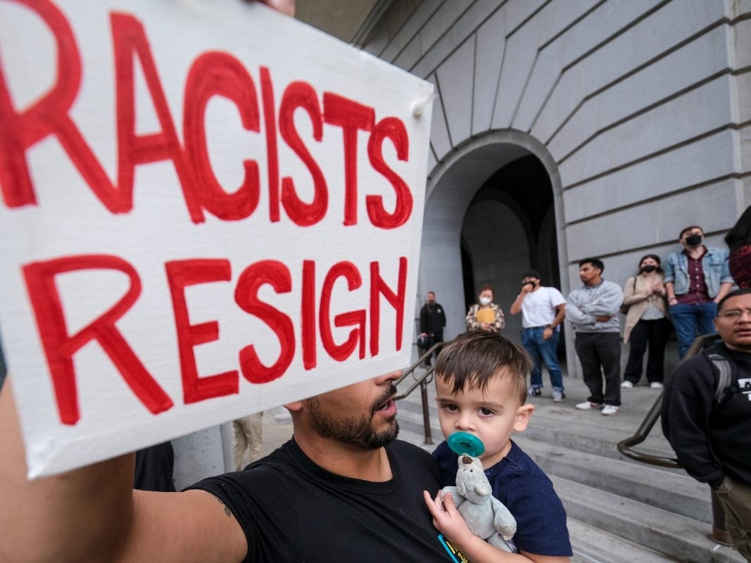 Shervin Aazami holding his son Barrett and a sign protest outside City Hall during the Los Angeles City Council meeting Tuesday, Oct. 11, 2022 in Los Angeles. 