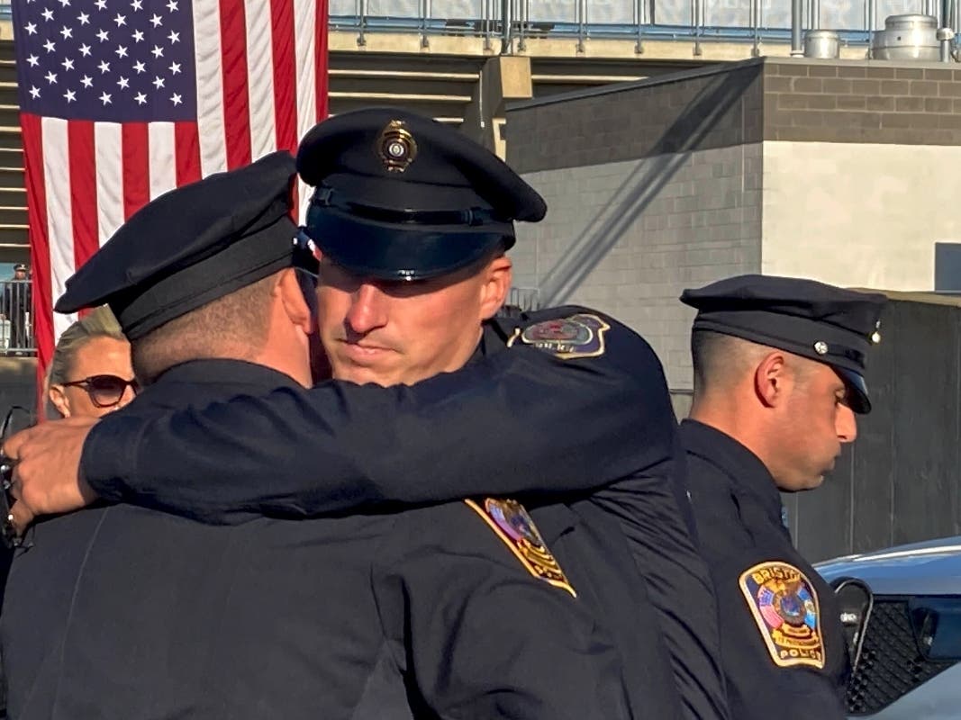 Two Bristol Police department officers hug before a joint police funeral, Friday, Oct. 21, 2022, in East Hartford, Conn.