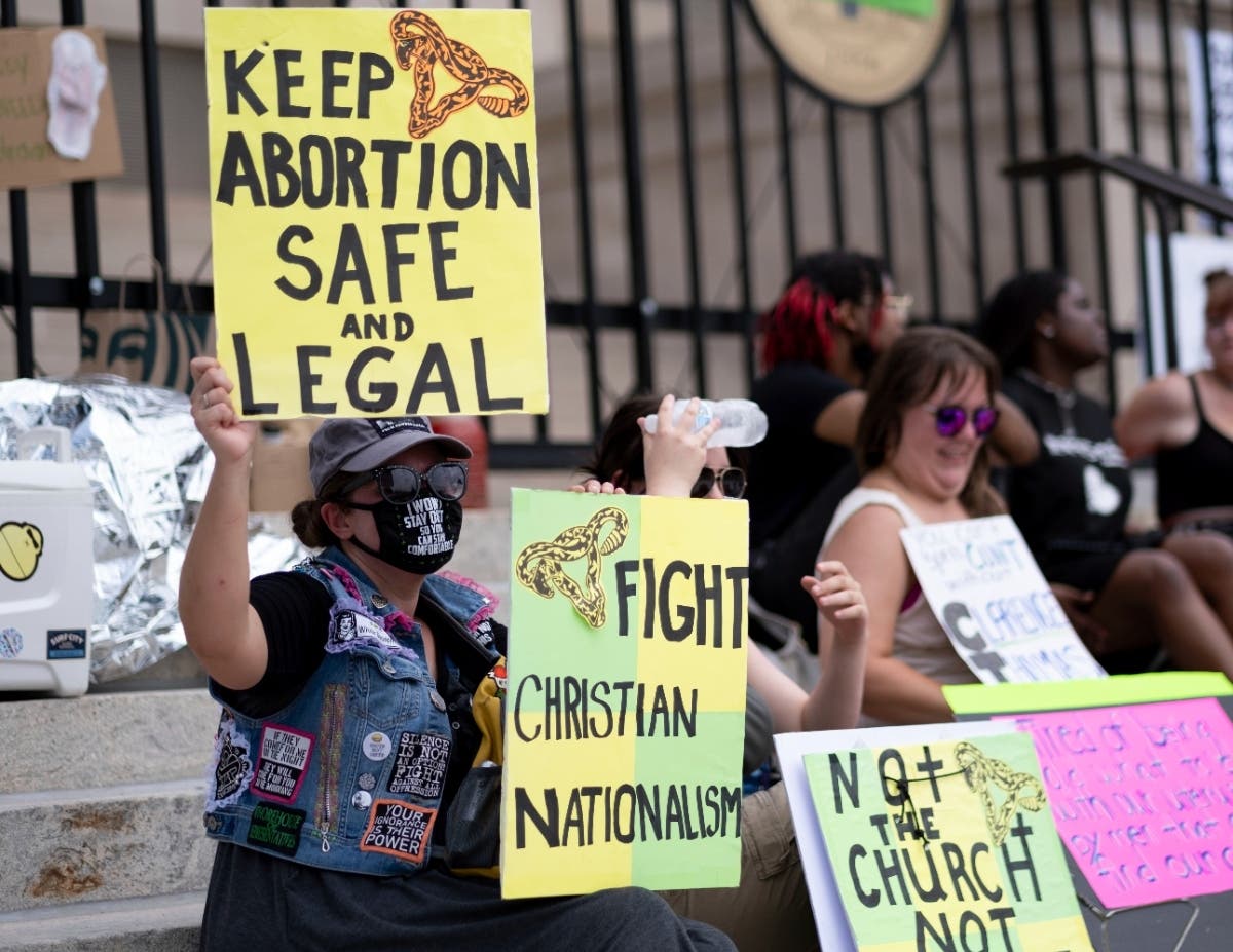 A small group, including Stephanie Batchelor, left, sits on the steps of the Georgia state Capitol protesting the overturning of Roe v. Wade on June 26, 2022.