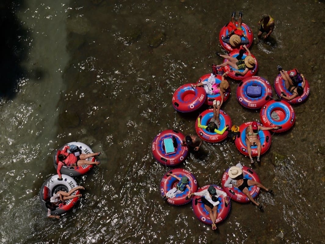 Tubers float the cool Comal River in New Braunfels, Texas, Thursday. Meteorologists say scorching temperatures brought on by a heat dome have taxed the Texas power grid and threaten to bring more record highs to the state over the 4th of July.