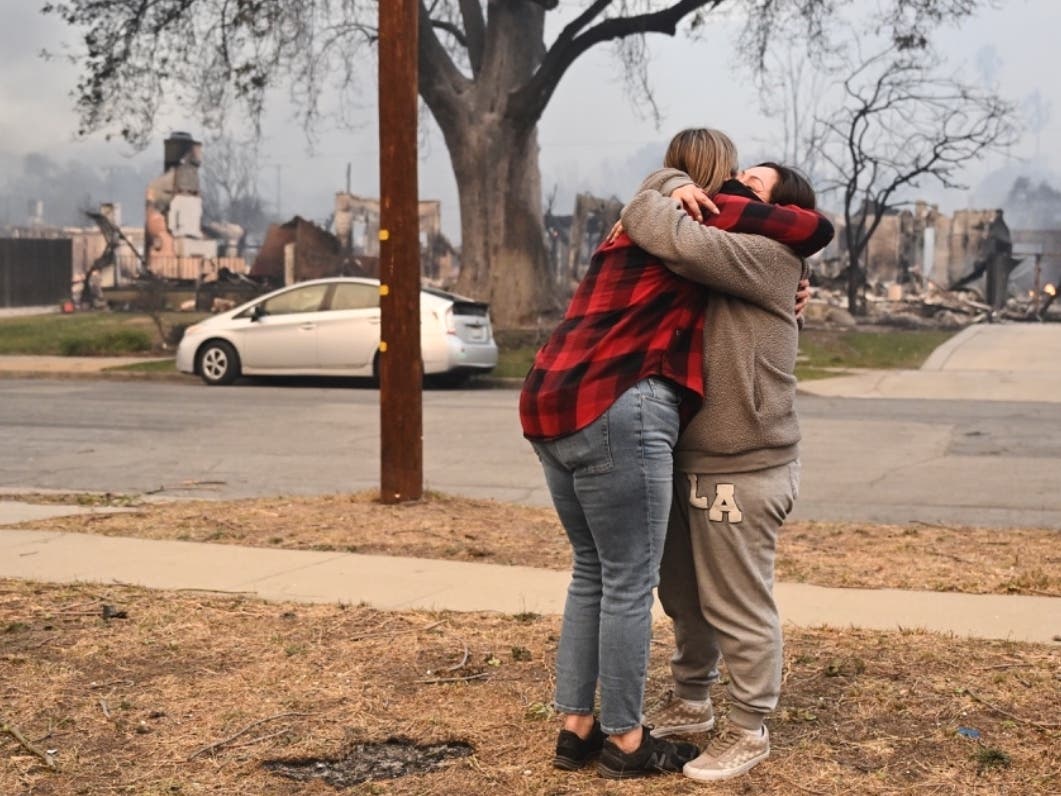 Lisa Diaz hugs a neighbor outside of their homes as the Eaton Fire sweeps through the area Wednesday, Jan. 8, 2025, in Altadena, Calif.