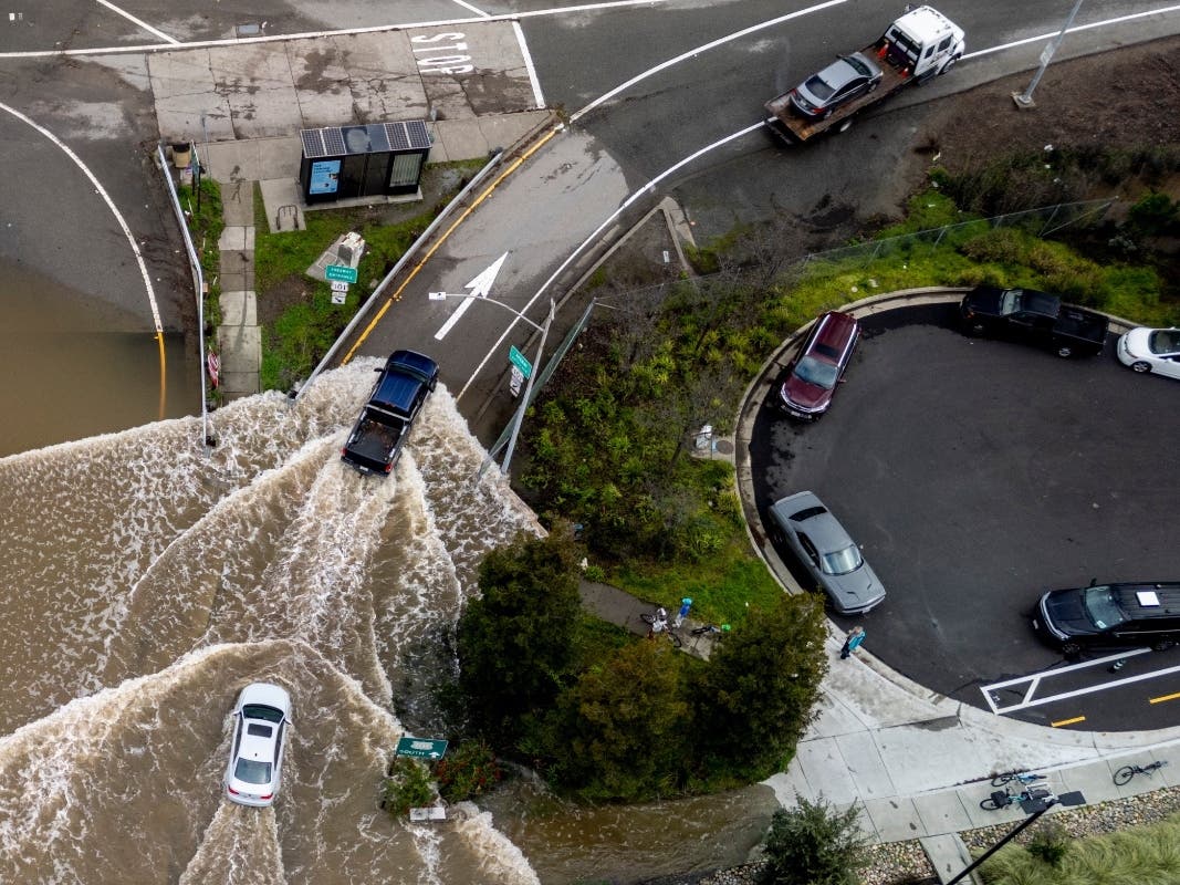 Vehicles drive on a flooded road during a king tide event in Corte Madera, Calif., Saturday, Jan. 3, 2026