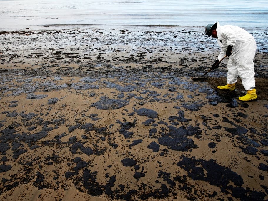 A worker removes oil from sand at Refugio State Beach, north of Goleta, Calif., May 21, 2015. 