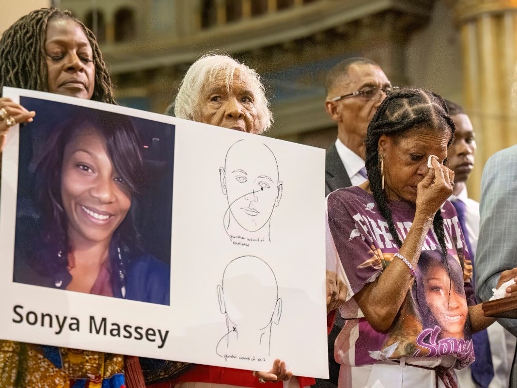 Donna Massey, center right, wipes tears from her face as she listens to Rev. Al Sharpton, right, speak during a press conference over the shooting death of her daughter, Sonya, who was killed by Illinois sheriff's deputy Sean Grayson.