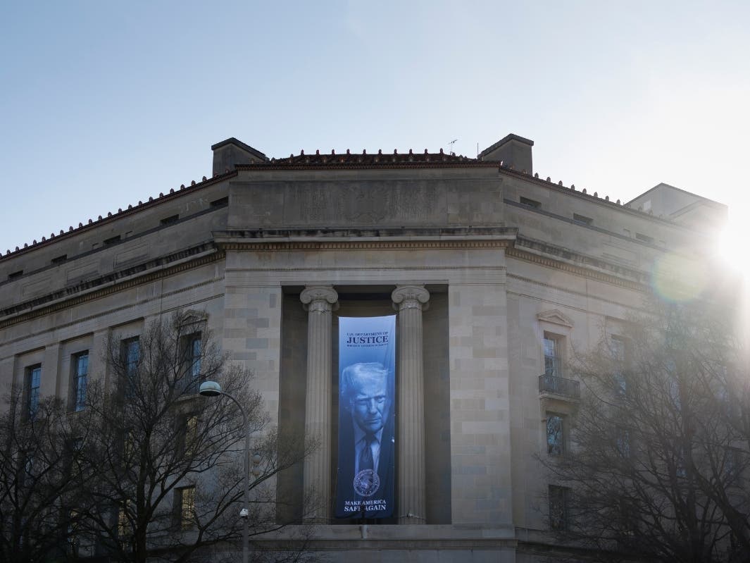A banner of President Donald Trump hangs outside the U.S. Department of Justice on Saturday, March 21, 2026, in Washington.