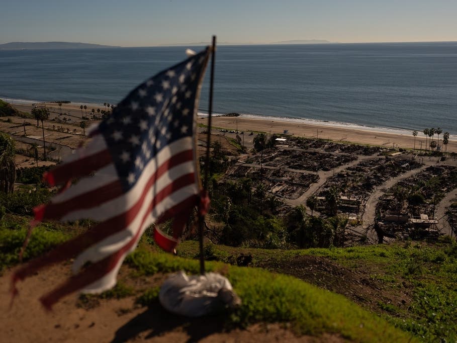 A tattered U.S. flag flaps in the wind over the remains of a mobile home park that was destroyed in the Palisades Fire along the Pacific Ocean, Dec. 5, 2025, in the Pacific Palisades neighborhood of Los Angeles. 