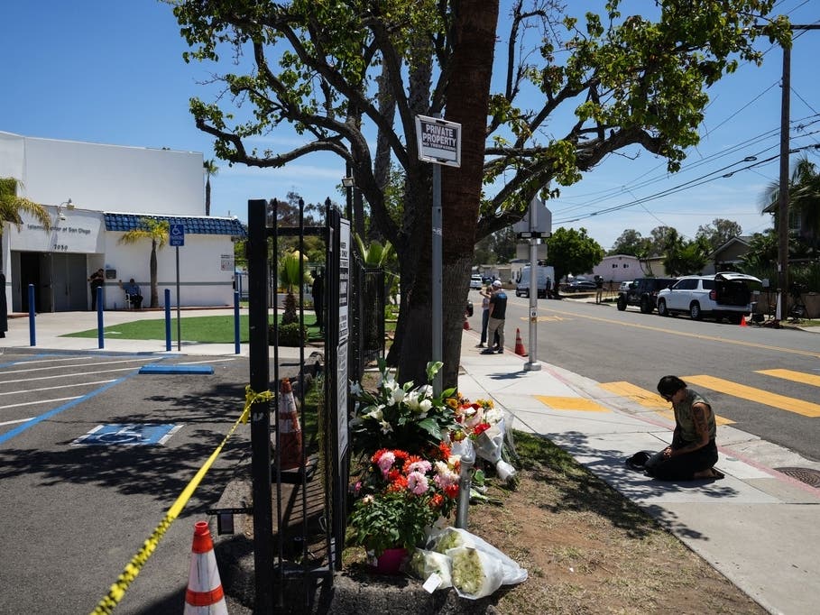 Nicole Witherow prays beside flowers placed outside of the Islamic Center of San Diego, a day after a shooting, Tuesday, May 19, 2026, in San Diego. 