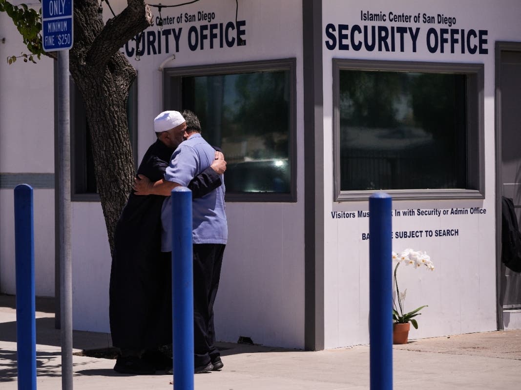 People embrace outside the security office of the Islamic Center of San Diego, a day after a shooting, Tuesday, May 19, 2026, in San Diego.