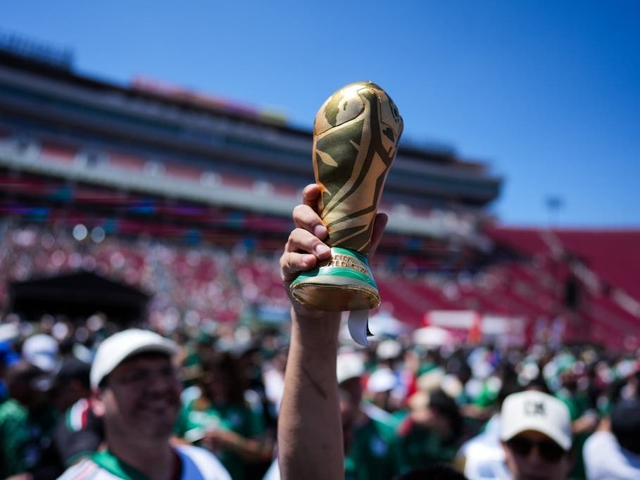 A fan holds up a replica of the World Cup trophy at a fan festival at the Los Angeles Memorial Coliseum in Los Angeles, Thursday, June 11, 2026, during a live broadcast of the World Cup soccer match between Mexico and South Africa. 