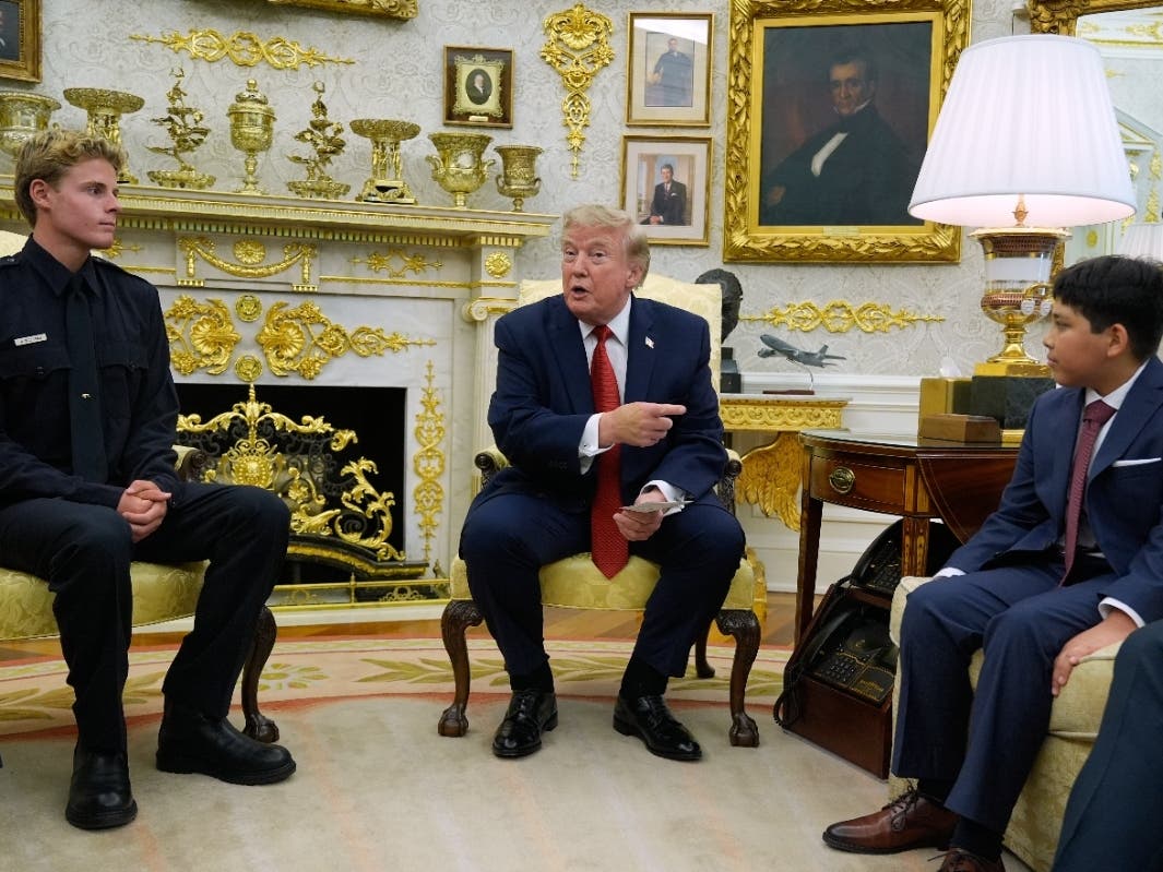 President Donald Trump gestures to Nathaniel Rai, the boy lifeguard Ryder Williams, left, saved as they meet in the Oval Office of the White House, Monday, Aug. 17, 2026, in Washington. 