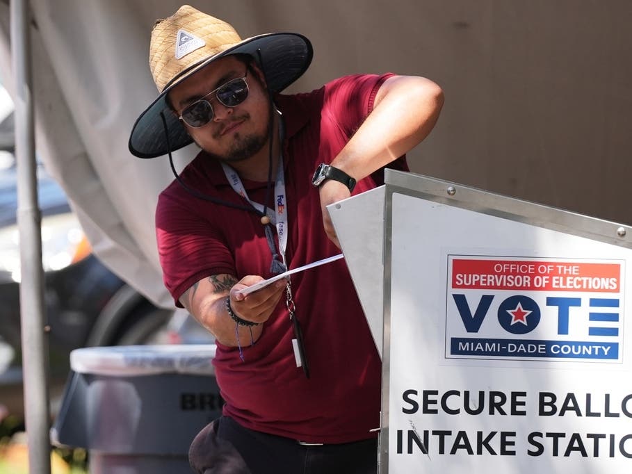 An election worker places a vote-by-mail ballot into a secure bin at the Miami-Dade County Supervisor of Elections Office during the Florida primary election in Doral on Tuesday, Aug. 18.