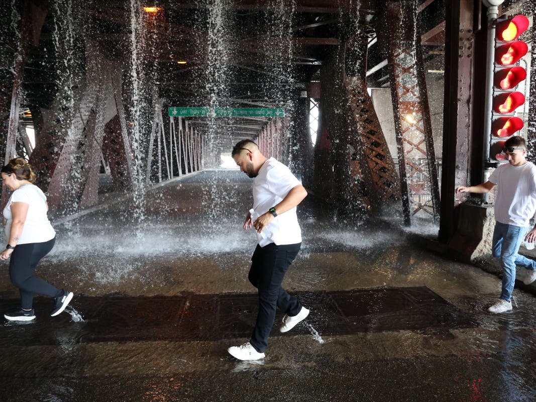 People scamper west across the lower level of the DuSable Lake Shore Drive bridge over the Chicago River on Wednesday as water pumped by a Chicago Fire Department boat flows down onto the double-leaf, double-deck, fixed counterweight bridge.