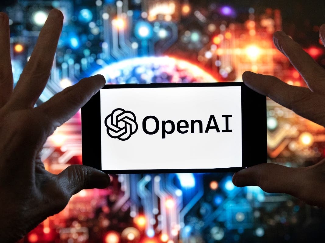 The OpenAI logo is displayed on a cell phone in front of an image generated by ChatGPT's Dall-E text-to-image model, Dec. 8, 2023, in Boston.