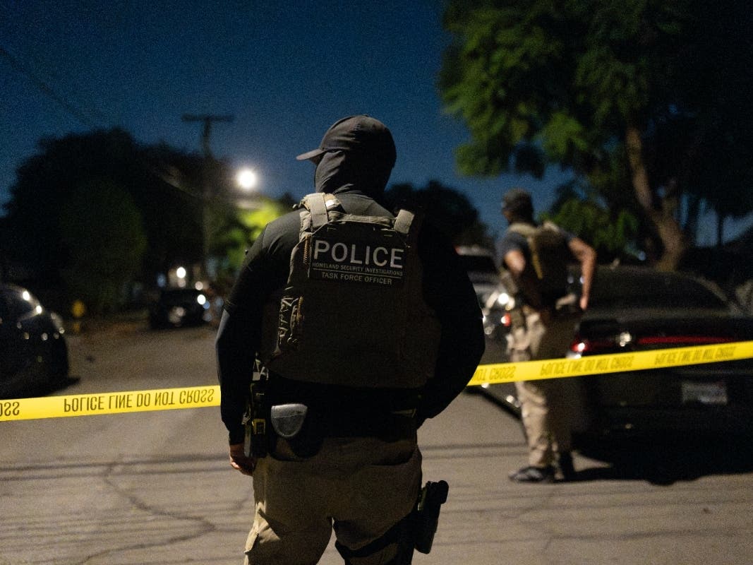 A Homeland Security Investigations task force officer stands near police tape marking a perimeter during a federal operation targeting suspected illegal voter registration in Commerce, Calif., Monday, Oct. 19, 2026. 