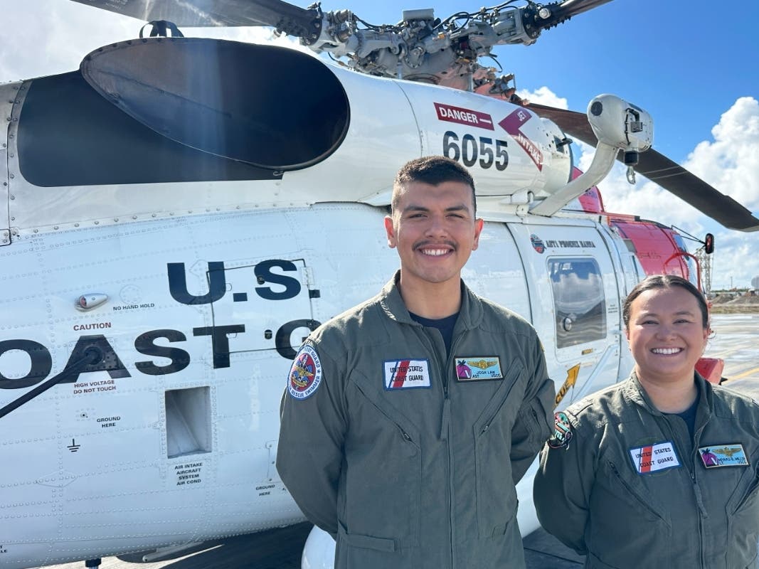This photo made with a smartphone shows U.S. Coast Guard officer Josh Law, left, and lieutenant Miyako Miller standing in front of a rescue helicopter at the U.S. Coast Guard Air Station in Ventura, Calif., Thursday, Oct. 22, 2026. 