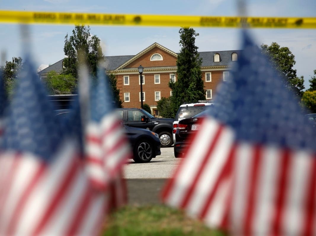 American flags, part of a makeshift memorial, stand at the edge of a police cordon in front of the municipal buildings.