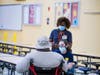 Nurse Liza Hart, back, and Jennie Mosbauer, a nutritionist, speak with a man at an emergency shelter set up due to Tropical Storm Eta at Middleton High School Wednesday in Tampa.
