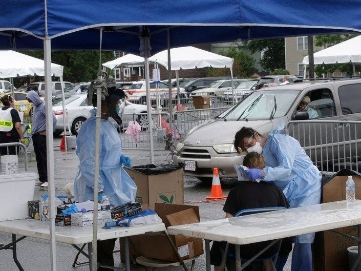 Medical workers administer tests for the coronavirus Thursday in Roxbury. 