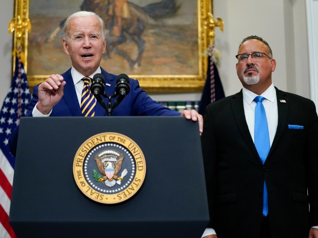 President Joe Biden speaks about student loan debt forgiveness in the Roosevelt Room of the White House, Wednesday, Aug. 24, 2022, in Washington. Education Secretary Miguel Cardona listens at right.
