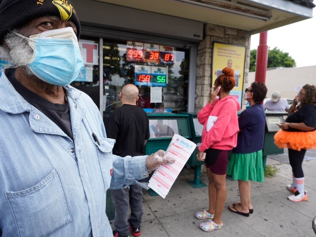 Philip Smith, wears a face mask and gloves as he lines up to purchase his lottery tickets for the Powerball lottery at the Blue Bird Liquor store in Hawthorne, Calif., Monday, Oct. 31, 2022.