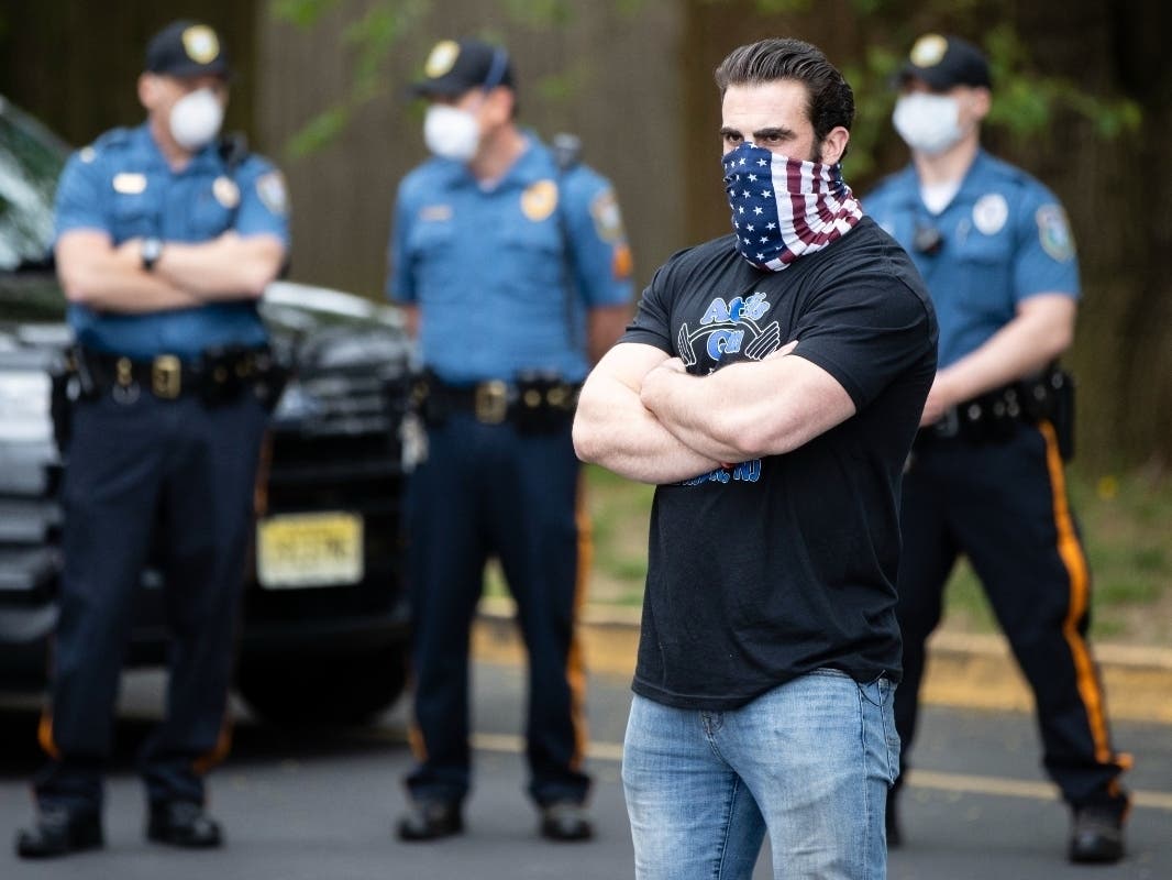 Atilis Gym co-owner Ian Smith stands outside the gym in Bellmawr, N.J., Monday, May 18, 2020 as police look on. The gym in New Jersey reopened for business early Monday, defying a state order that shut down nonessential businesses.