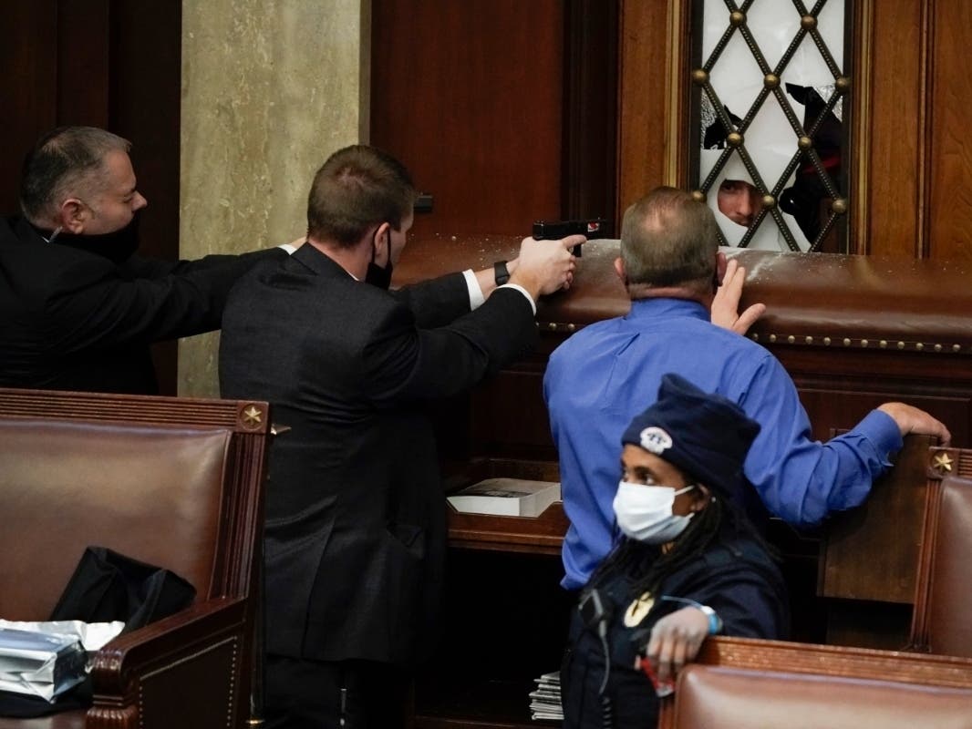 Police with guns drawn watch as protesters try to break into the House Chamber at the U.S. Capitol on Wednesday, Jan. 6, 2021, in Washington.