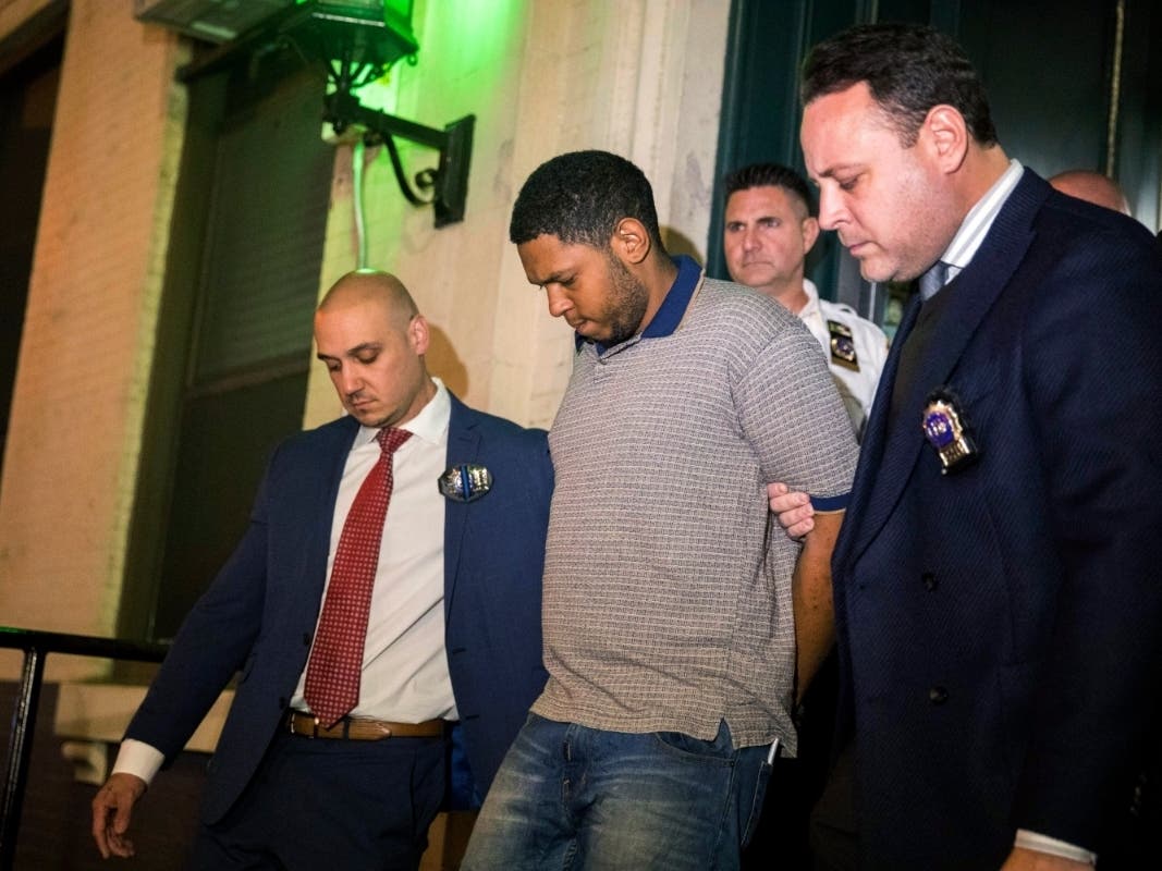 Officers escort Randy Santos from the Fifth Precinct to a vehicle bound for a hospital for evidence collection, Oct. 5, 2019.