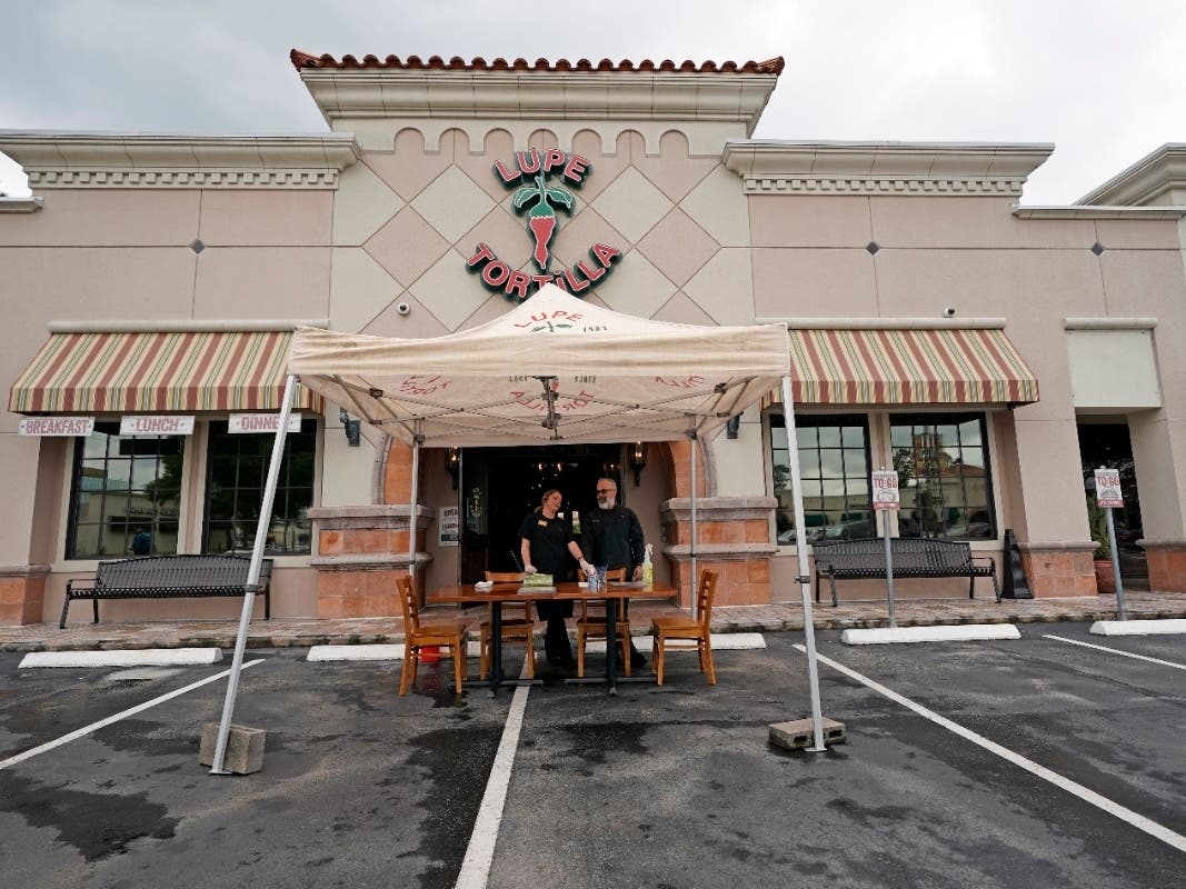 Pablo Cardona (right) and Nikki Veney wait to handle curbside to-go orders Wednesday outside a Lupe Tortilla restaurant in Houston.