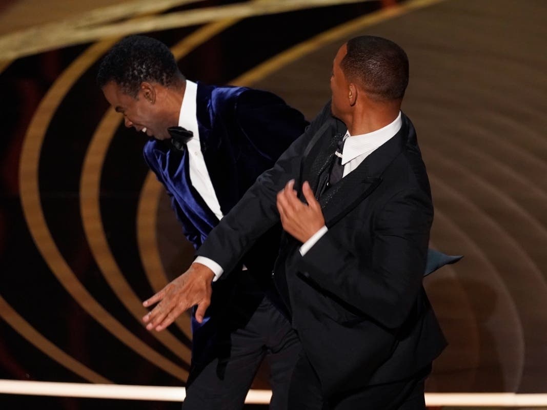 Will Smith, right, hits presenter Chris Rock on stage while presenting the award for best documentary feature at the Oscars on Sunday, March 27, 2022, at the Dolby Theatre in Los Angeles.