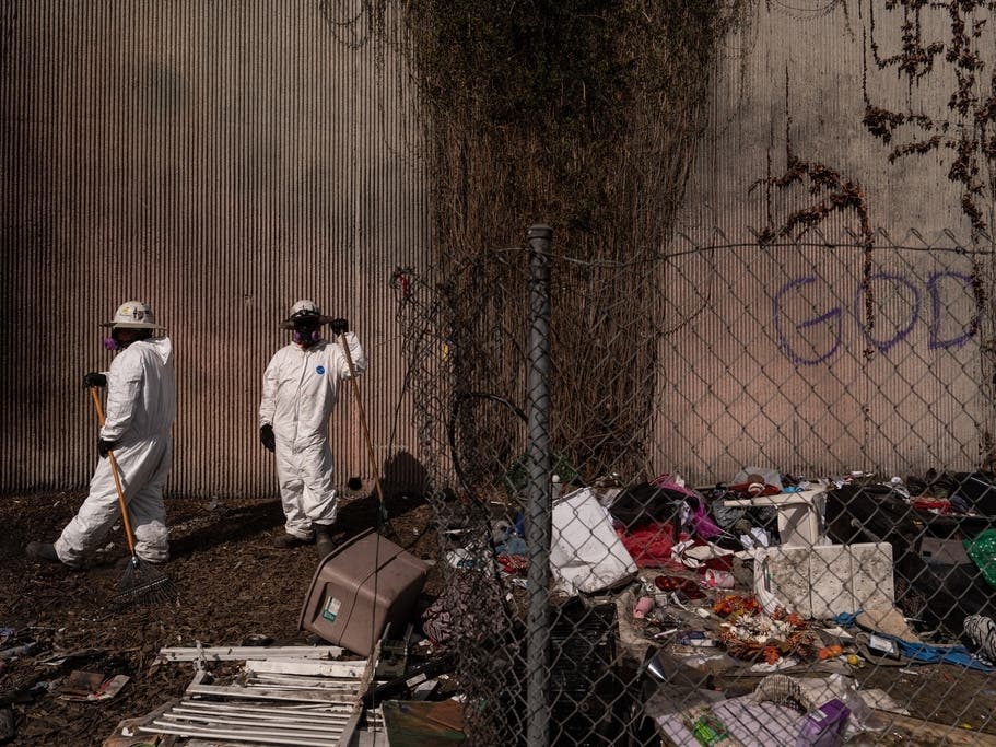 Workers pause while clearing a homeless encampment along the 110 Freeway in Los Angeles. 