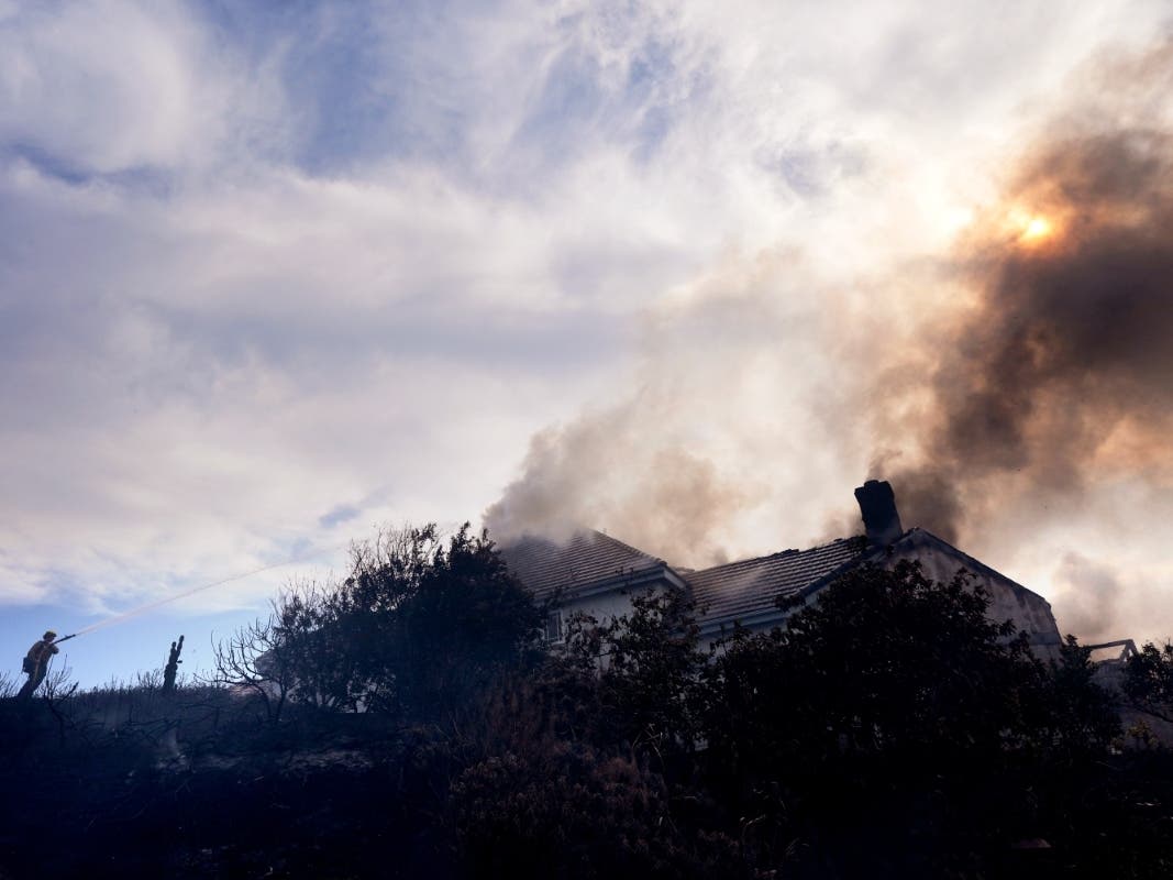 A firefighters works to put out a fire on a house engulfed in flames during the Norte Fire on Friday, Oct. 16, 2026, in San Juan Capistrano.