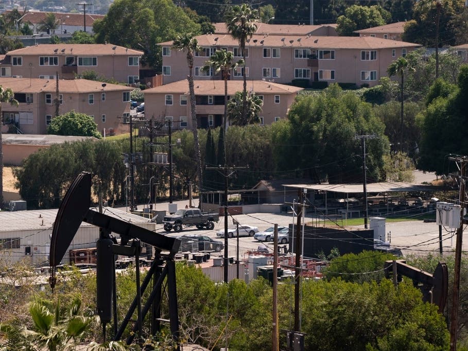 Apartment buildings rise behind pump jacks operating at the Inglewood Oil Field in Los Angeles.