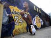 A fan pays respects at a mural depicting Kobe Bryant in a downtown Los Angeles alley after word of the Lakers star's death in a helicopter crash, in downtown Los Angeles Sunday, Jan. 26, 2020.