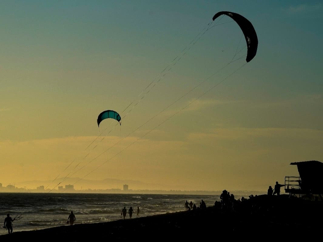 Beachgoers watch kite surfers Tuesday, May 5, 2020, in Huntington Beach, CA. Gov. Gavin Newsom gave approval Tuesday to plans by Huntington Beach and two smaller cities to reopen beaches that fell under his order shutting them down.