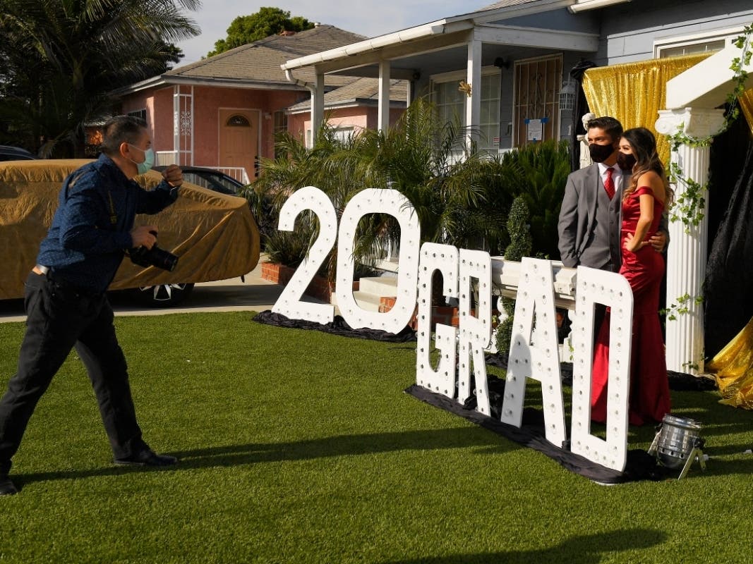 Gabriel Lopez, center, and Delilah Santos, right, have their pictures and video taken by Philippe Michel in front of the home of Diane Scott during the coronavirus outbreak, Saturday, May 16, 2020, in Los Angeles. 