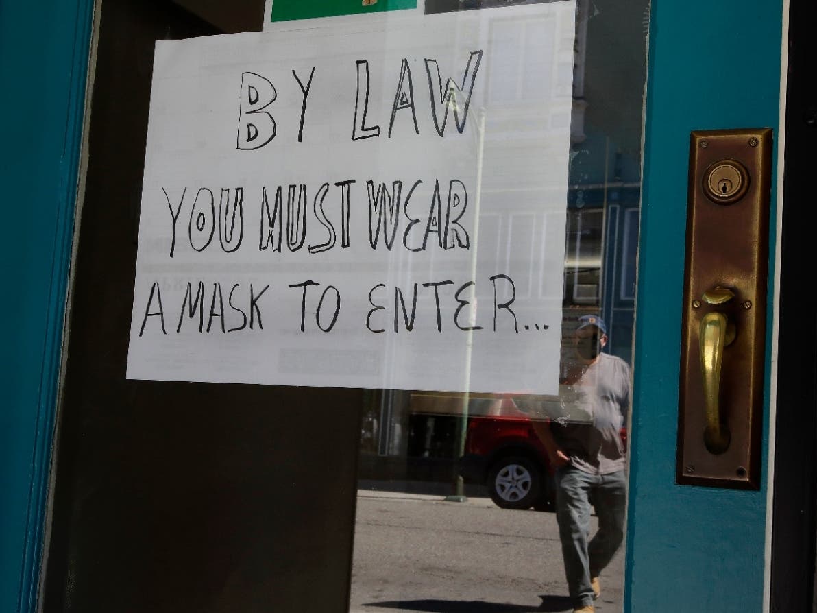 A man wearing a mask prepares to enter a restaurant providing take out food on Wednesday, April 22, 2020, in Alameda, Calif.