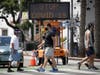 Pedestrians wear masks as they cross a street amid the coronavirus pandemic Sunday, July 12, 2020, in Santa Monica, Calif. A heat wave has brought crowds to California's beaches as the state grappled with a spike in infections and hospitalizations.