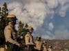 Deputies with the San Bernardino County Sheriff's department stand guard as the smoke from the Apple Fire billows behind them, Saturday, Aug. 1, 2020, in Yucaipa, Calif. A clash erupted after Black Lives Matter protesters interrupted a pro-Trump event.