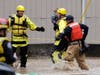 A firefighter carries Harlyn Alves, 2 years old, along a rope line and to high ground as his four-member family was evacuated from their apartment building Thursday, Feb. 6, 2020, in Issaquah, Wash.