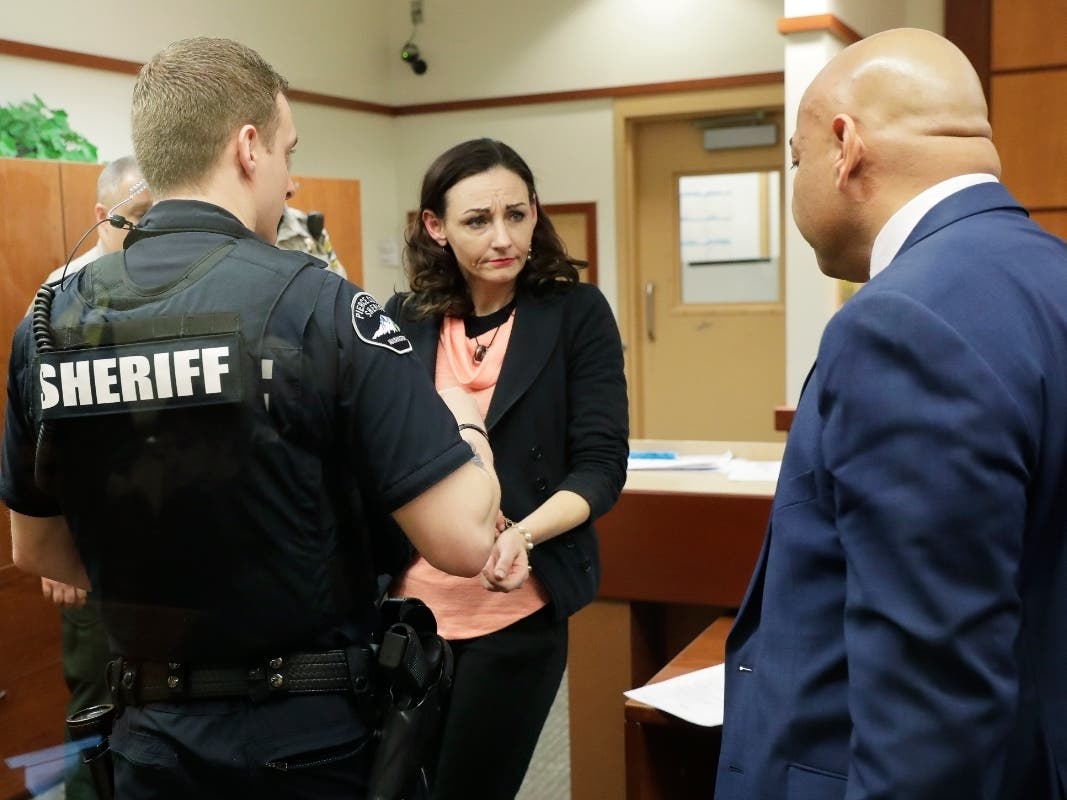 Juliette Parker, center, looks to her attorney at right as she hands over jewelry before being handcuffed by a Pierce County Sheriff's Deputy, left, Tuesday, Feb. 18, 2020, in a Pierce County courtroom in Tacoma, Wash.