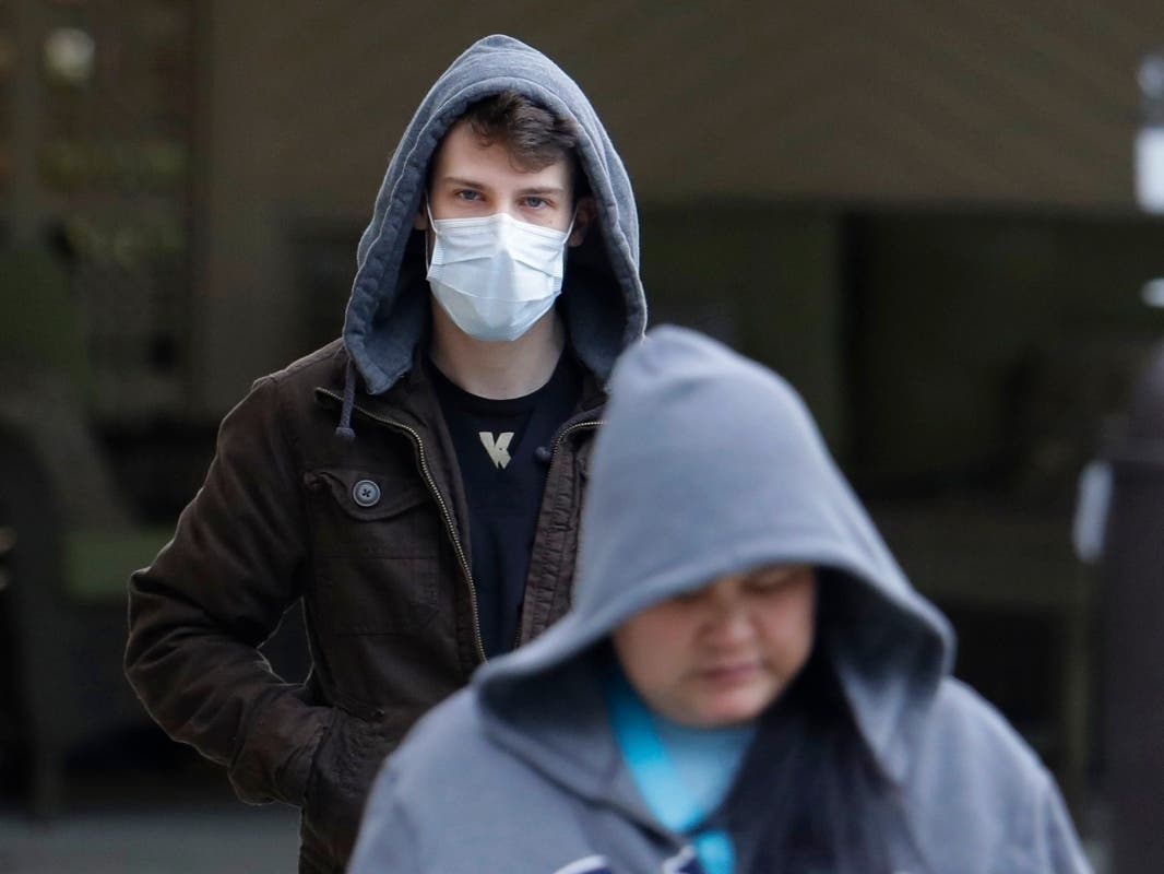 A man wearing a mask Tuesday walks away from the entrance of the Life Care Center in Kirkland, Washington, near Seattle. The facility has been tied to several confirmed cases of the nee coronavirus.