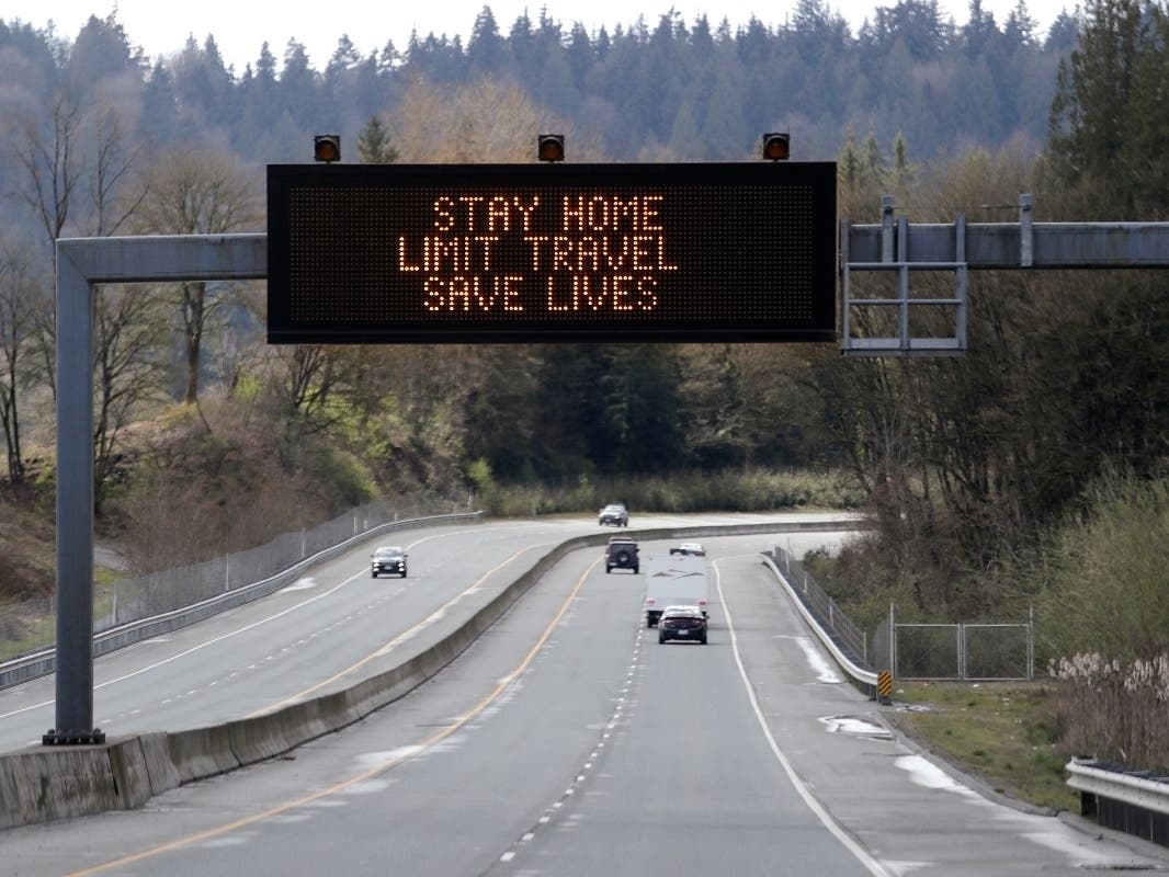 A sign overhead on an unusually quiet highway reminds drivers to "Stay home, limit travel, save lives" as part of Gov. Jay Inslee's ongoing stay-at-home order in the midst of the coronavirus outbreak, Wednesday, April 1, 2020, in Monroe, Wash.