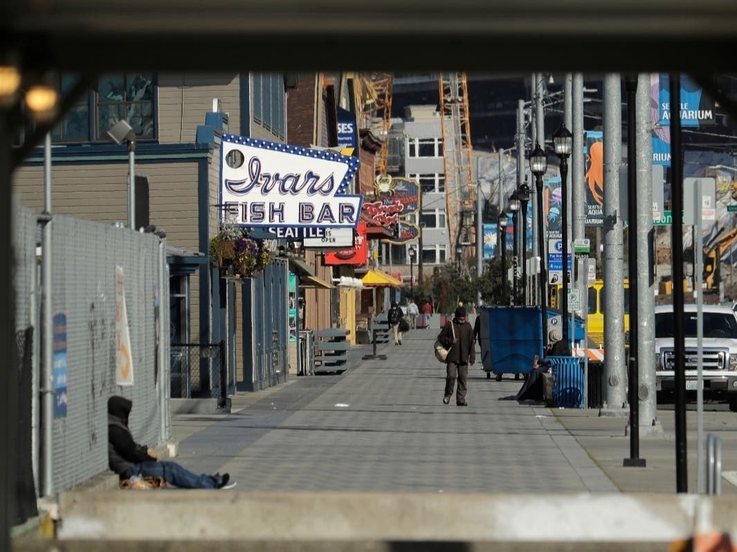The sidewalk along Alaskan Way in front of Seattle's iconic Ivar's Fish Bar restaurant is nearly empty, Friday, April 10, 2020, as seen from a construction walkway near the Colman Ferry Terminal in Seattle.