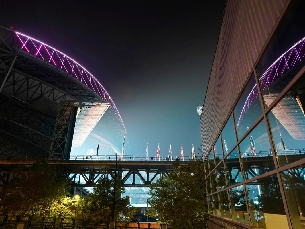 Smoke from wildfires is seen in the air as lights from T-Mobile Park, left, are reflected in a window of CenturyLink Field on Thursday, Sept. 10, 2020, in Seattle.
