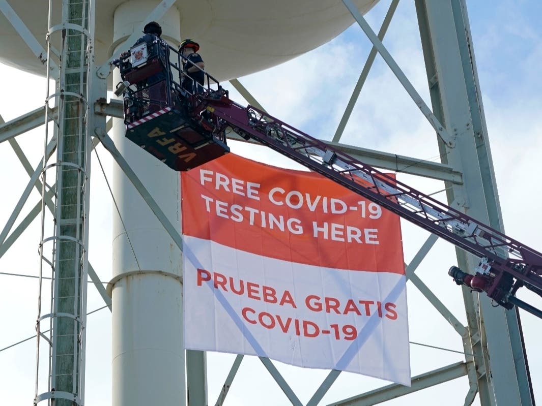Firefighters on a Valley Regional Fire Authority ladder truck hang a banner on a water tower at a King County COVID-19 testing site in Auburn, Wash., south of Seattle, on Oct. 28.